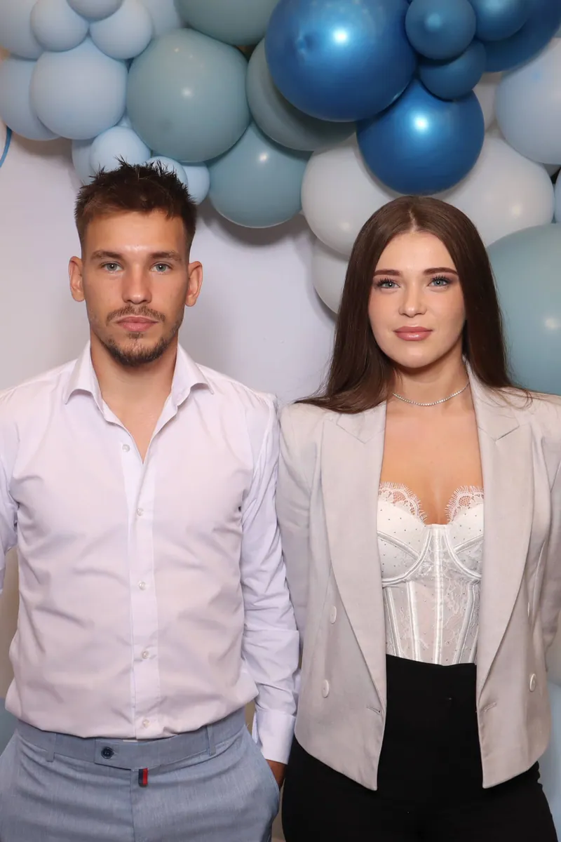 Fotografia făcută la cabină, înainte de transformare: doi invitați în fața unui decor cu baloane